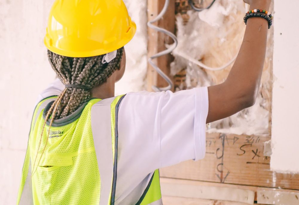 Construction worker fitting insulation into a framed interior wall before drywall is installed