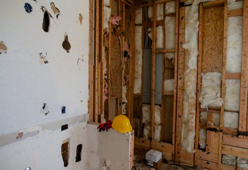 Opened wall cavity during renovation showing studs and existing insulation