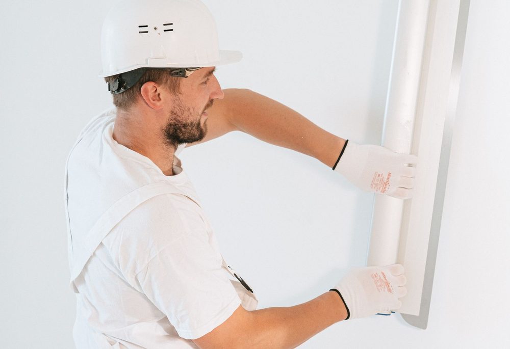 Installer fixing a plasterboard layer to a prepared wall